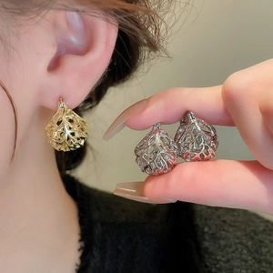 Close-up of vintage hollow flower basket earrings in polished gold and silver finishes