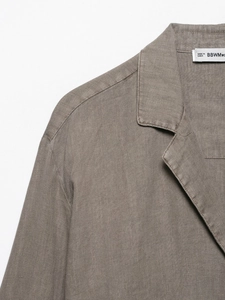 Detailed close-up of brown linen shirt fabric texture and collar stitching craftsmanship
