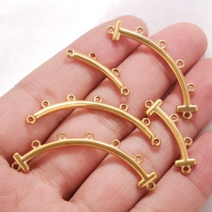 Bohemian gold curved multi-hole connectors for DIY jewelry shown on a hand for scale
