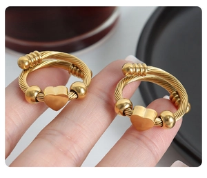 Macro view of gold twisted cable ring featuring a polished heart charm and beads