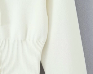 Vista dettagliata della trama in maglia bianca e della vita a coste del set maglione