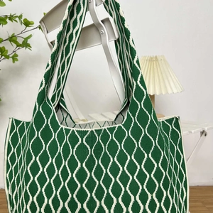 Detailed close-up of green and white wavy knit texture on a large tote bag hanging on a chair