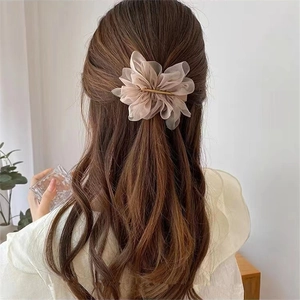Détail d'une pince à cheveux fleur en organza rose sur une femme avec fermoir doré