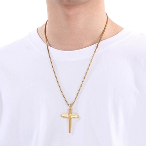 Gros plan du pendentif croix en forme de clou doré sur une chaîne maille box
