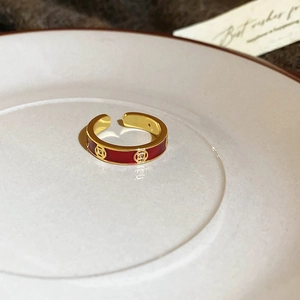 Detailed view of adjustable 18k gold plated ring with red enamel finish on white plate