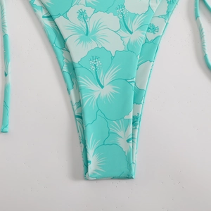 Detail of mint green bikini bottoms featuring white hibiscus floral print and fabric texture