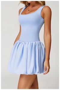 Detail of light blue sleeveless tennis dress featuring a U-neck and pleated bubble hem