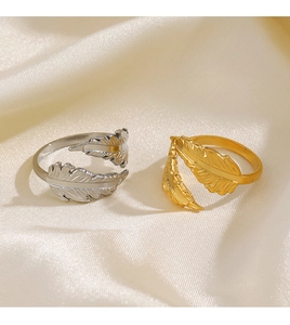 Detail view of gold and silver feather rings with textures on beige silk background