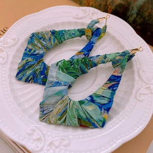 Macro detail of large geometric earrings wrapped in blue and green oil painting style fabric