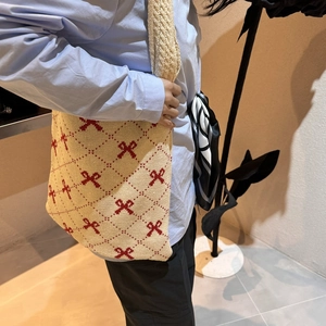 Detaillierte Stricktasche mit roten Schleifenmustern und gewebter Textur auf beiger Tasche