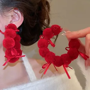 Big red pom pom earrings with bow accents on large hoops for Christmas festive outfits