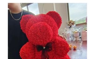 Close-up of 40cm red rose bear handmade with artificial flowers and a black ribbon bow