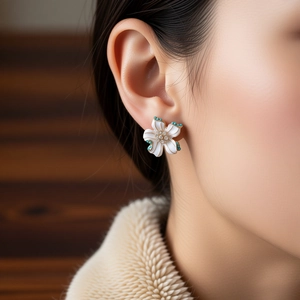 Close-up of vintage flower earrings with white petals and green stones on model