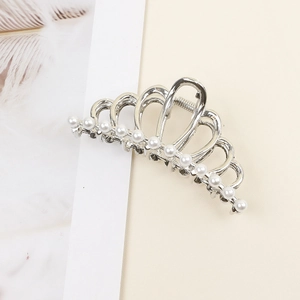 Detail of silver crown hair claw clip with embedded pearls on a minimalist background