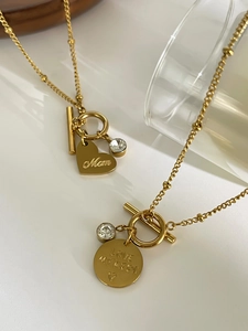 Detail of gold heart and round pendants with Mom engraving and crystal on OT clasp chain