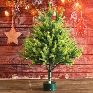 Miniature flocked Christmas tree with LED lights on a wooden table for home festive decor