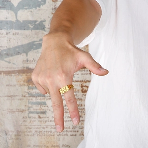 Macro detail of men's gold square ring with engraved vintage textured pattern