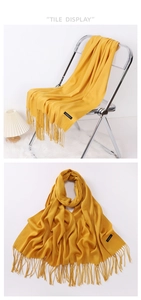 Detail of premium ginger yellow cashmere scarf featuring soft fringes and fine texture