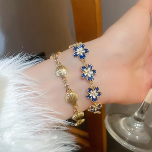 Detail of vintage gold shell and flower bracelet set on model with elegant styling