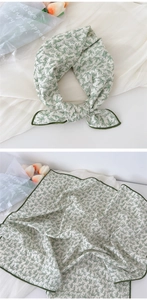 Detail of white cotton linen scarf with green leaf pattern and stitched edges