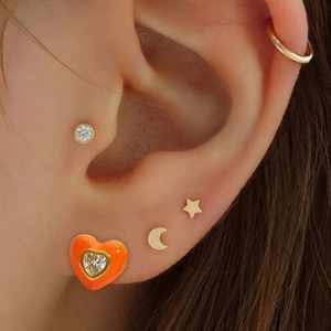 Orange heart-shaped stainless steel earrings with sparkling center crystal on ear lobe