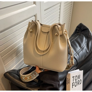 Detail of beige leather bucket bag with ethnic patterned wide woven shoulder strap