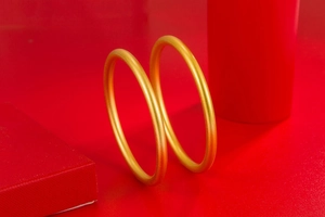 Detailed macro shot of two golden matte finish bangles on a red jewelry box