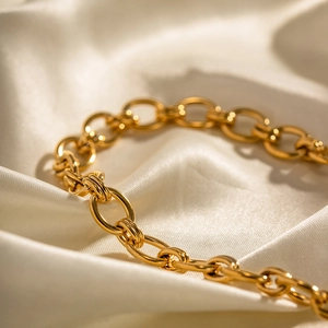 Détail macro d'une chaîne à gros maillons plaquée or 18 carats sur tissu de soie blanc