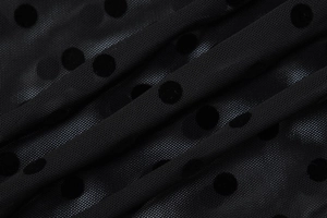Gros plan sur un tissu en maille noire à pois avec une matière transparente et respirante