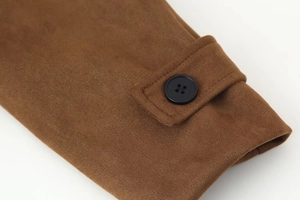 Close-up of brown suede jacket cuff with decorative black button and textured stitching