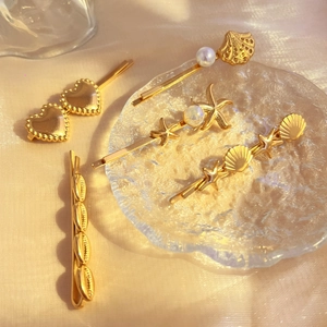 Golden metal hair clips set with pearls, shells and starfish on elegant beige fabric
