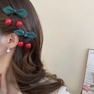 Detailed view of cherry bow hair clips on long hair with elegant green satin ribbon