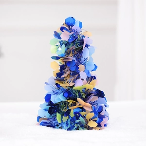 Detail of colorful mini Christmas tree with metallic tinsel and sequins on white snow base