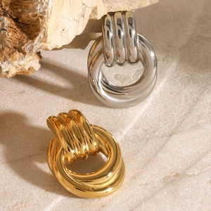 Intertwined gold and silver geometric steel brooches on natural textured stone background