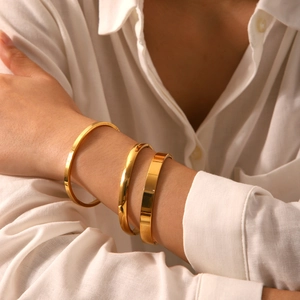 Three-piece set of minimalist gold-plated stainless steel bangles worn by a model