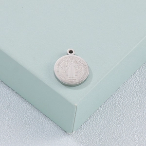 Detailed close-up of a silver Saint Benedict medal pendant with sharp embossed relief