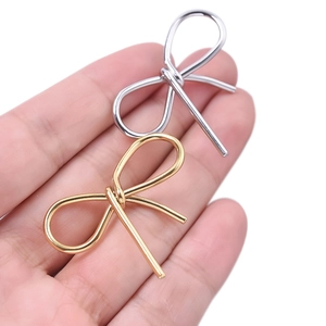 Vue détaillée de pendentifs nœuds en acier inoxydable 304 or et argent sur une main