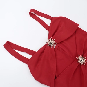 Detail of red fishtail dress featuring a golden sun-shaped metal buckle on the shoulder strap
