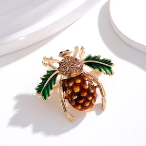 Détail macro d'une broche scarabée avec texture pomme de pin et ailes vertes