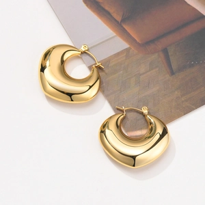 Detailed view of chunky golden hollow hoop earrings on a minimalist magazine backdrop
