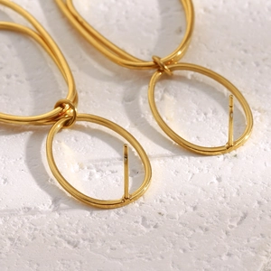 Close-up of 18K gold plated interlocking oval hoop earrings on white texture