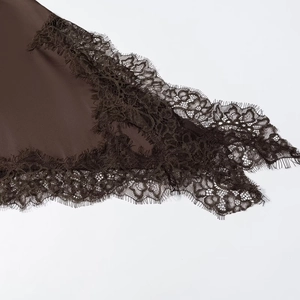 Detailansicht aus dunkelbraunem Satin mit aufwendigem Spitzenbesatz am Saum des Kleids