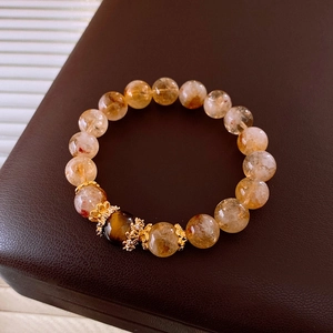 Detailed macro view of yellow rutilated quartz beads and tiger eye stone with gold spacers