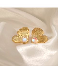 Detailed macro view of gold ginkgo leaf earrings with central iridescent gemstone