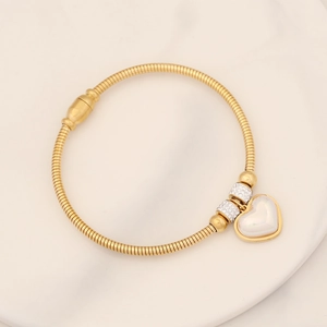 Detail of gold snake chain bracelet featuring heart charm and sparkling crystal beads