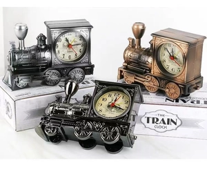 Three train-shaped alarm clocks in black, bronze, and dark metallic finishes