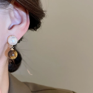 Detailed view of elegant gold drop earrings featuring white shell and brown resin beads