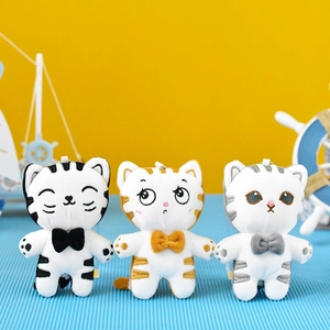 Three cute striped cat plush keychains with bowties in white, yellow, and blue colors