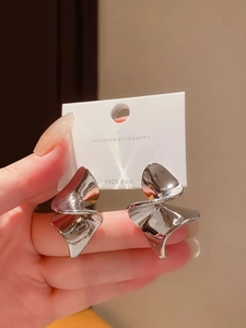 Gros plan sur des boucles d'oreilles abstraites argentées torsadées avec tiges en S925