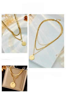 Close-up of triple-layered gold chain necklace with coin pendant and portrait engraving